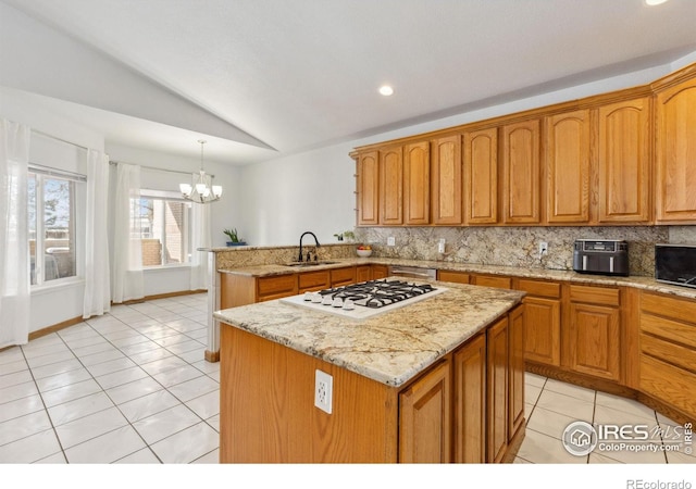 kitchen with a sink, hanging light fixtures, white gas cooktop, and a kitchen island