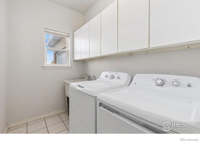 laundry area featuring cabinet space, light tile patterned floors, baseboards, and separate washer and dryer