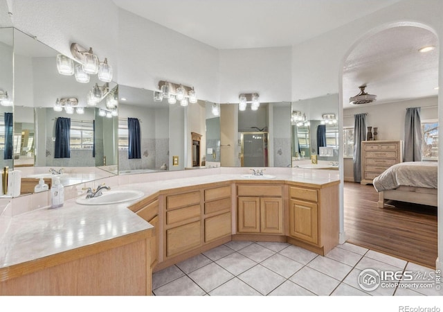 ensuite bathroom with double vanity, ensuite bath, tile patterned flooring, and a sink