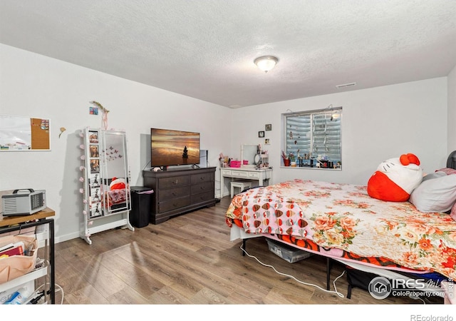 bedroom featuring a textured ceiling and wood finished floors