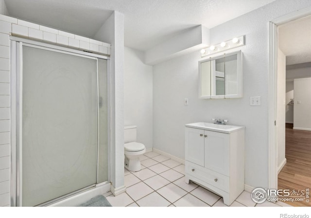 bathroom featuring toilet, tile patterned flooring, a textured ceiling, vanity, and a shower stall