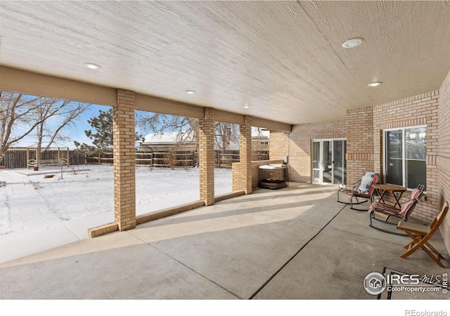 snow covered patio featuring a fenced backyard