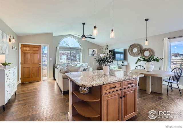 kitchen featuring brown cabinets, a kitchen island, open floor plan, and dark wood finished floors