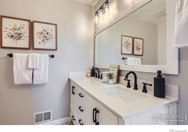 full bath featuring visible vents, a sink, baseboards, and double vanity