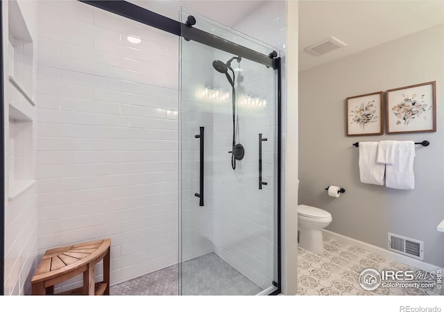 bathroom with a stall shower, baseboards, visible vents, and toilet