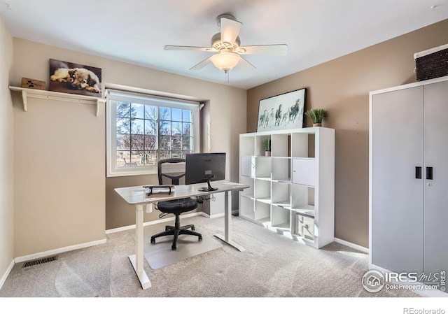 office space featuring baseboards, ceiling fan, visible vents, and light colored carpet