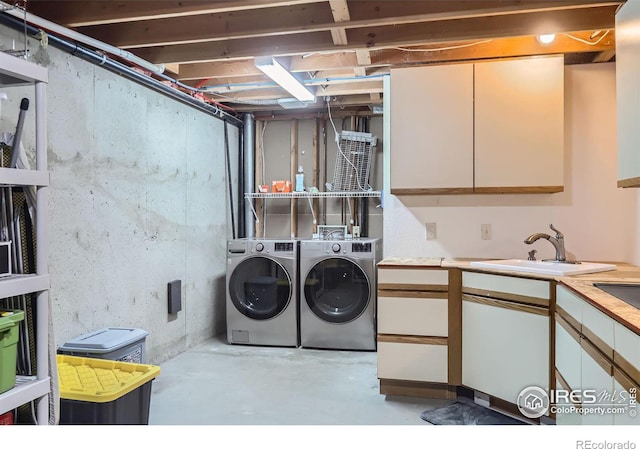 washroom featuring cabinet space, washer and clothes dryer, and a sink