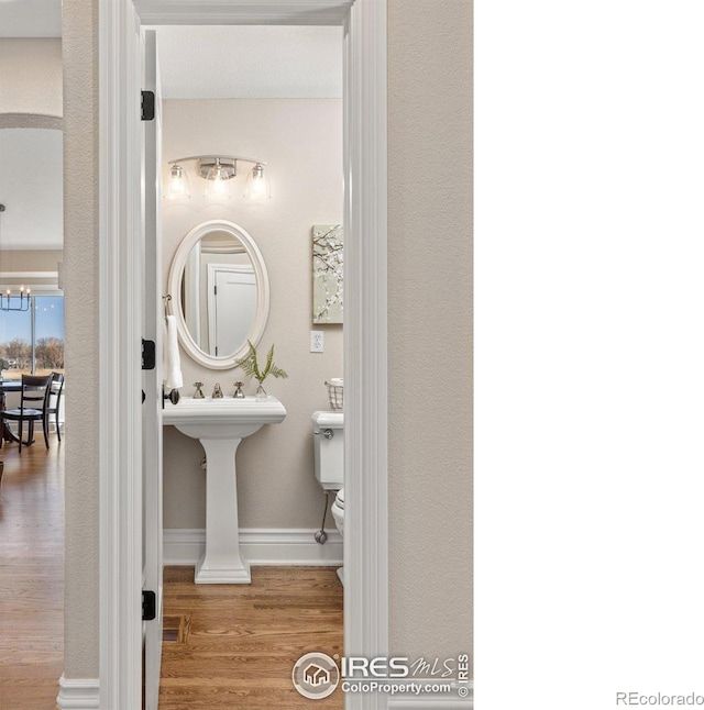 bathroom featuring toilet, an inviting chandelier, baseboards, and wood finished floors