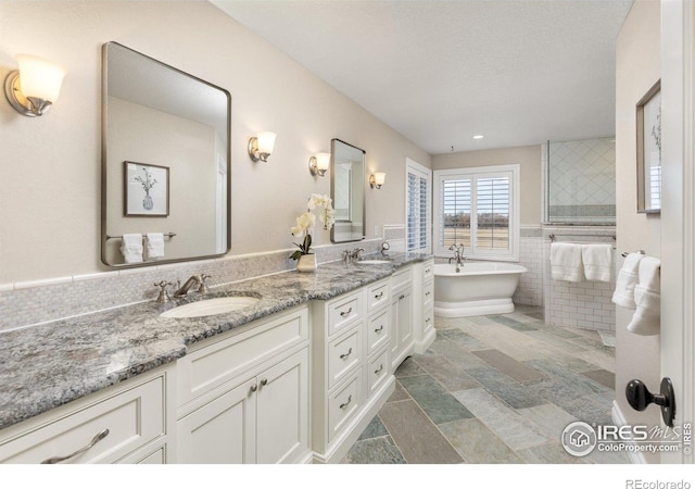 bathroom featuring a sink, tile walls, a freestanding bath, and double vanity