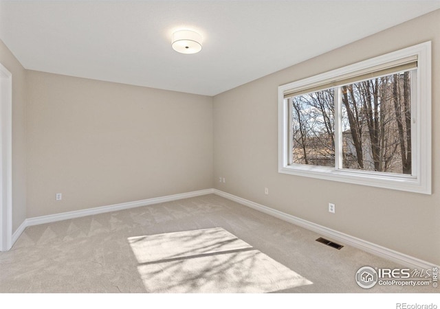 empty room featuring light carpet, baseboards, and visible vents