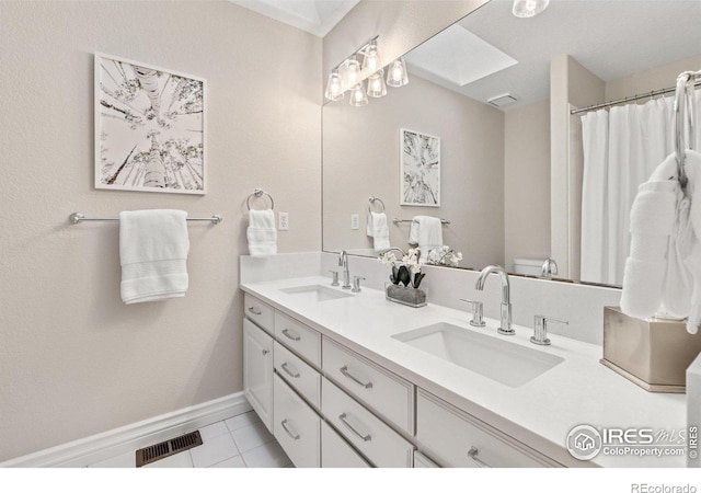 full bath featuring double vanity, a skylight, a sink, and visible vents