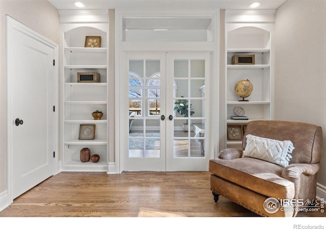 sitting room with light wood-style floors, recessed lighting, french doors, and built in features