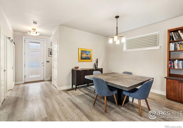 dining space featuring light wood-style flooring and baseboards