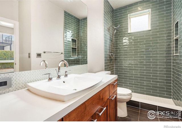 bathroom with toilet, a tile shower, decorative backsplash, and vanity