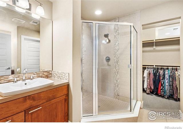 bathroom featuring vanity, a stall shower, a walk in closet, and visible vents