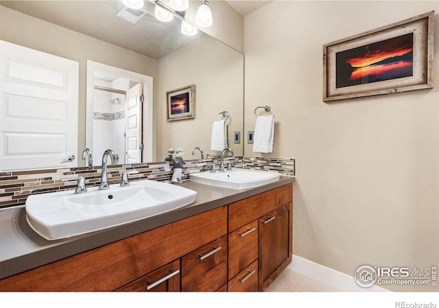 full bath featuring double vanity, baseboards, backsplash, and a sink