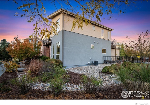 property exterior at dusk with cooling unit and stucco siding