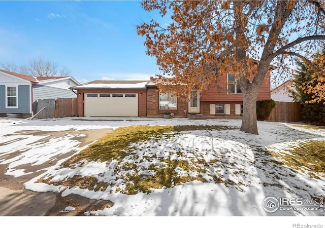 tri-level home with brick siding, fence, and an attached garage