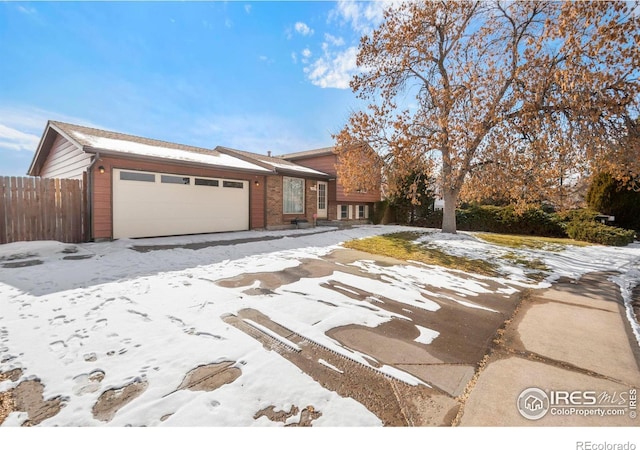 view of front of property with an attached garage, fence, and brick siding