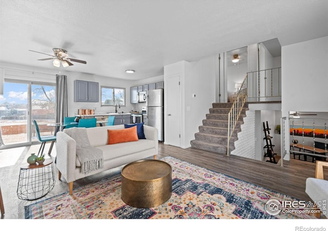 living area featuring a ceiling fan, stairway, and wood finished floors