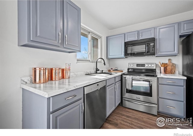 kitchen featuring dark wood finished floors, gray cabinets, a sink, and black appliances