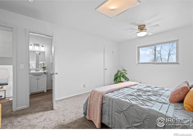 bedroom featuring ensuite bath, baseboards, a sink, and light colored carpet