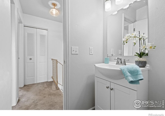 bathroom with a closet, a textured wall, and vanity