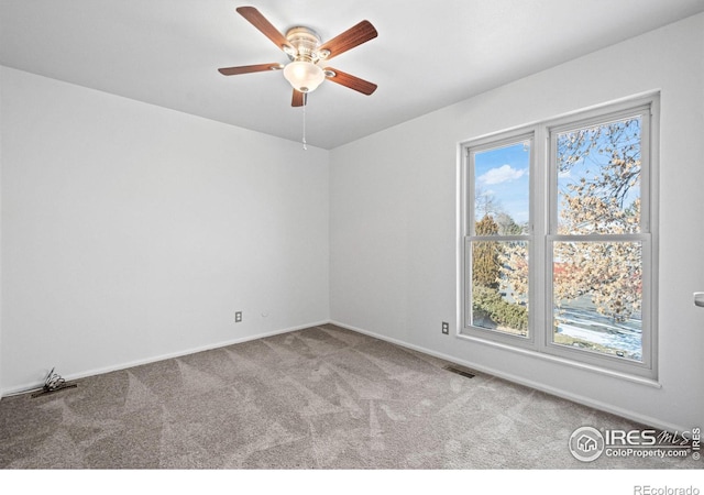 spare room with a ceiling fan, visible vents, light carpet, and baseboards