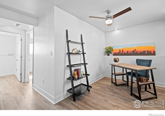 office space featuring a ceiling fan, visible vents, baseboards, and wood finished floors