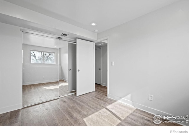 unfurnished bedroom with a closet, recessed lighting, wood finished floors, and baseboards