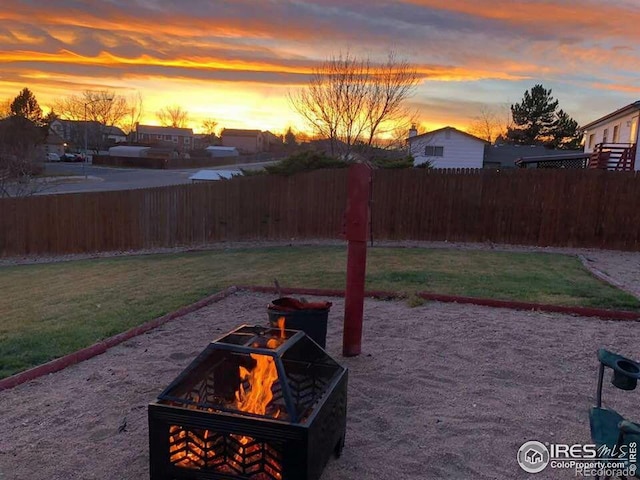 yard at dusk featuring a fire pit and fence