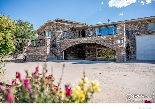 view of front of house with stairs, concrete driveway, brick siding, and a garage