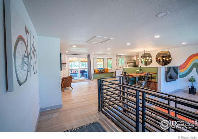 corridor featuring recessed lighting, a textured ceiling, an upstairs landing, and wood finished floors