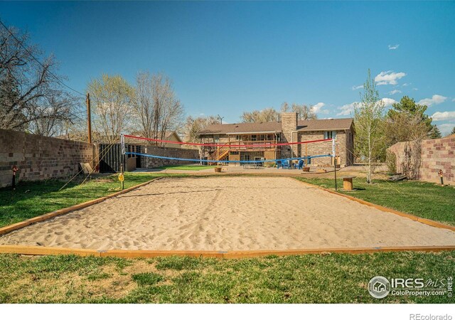 view of home's community with a lawn, volleyball court, and fence