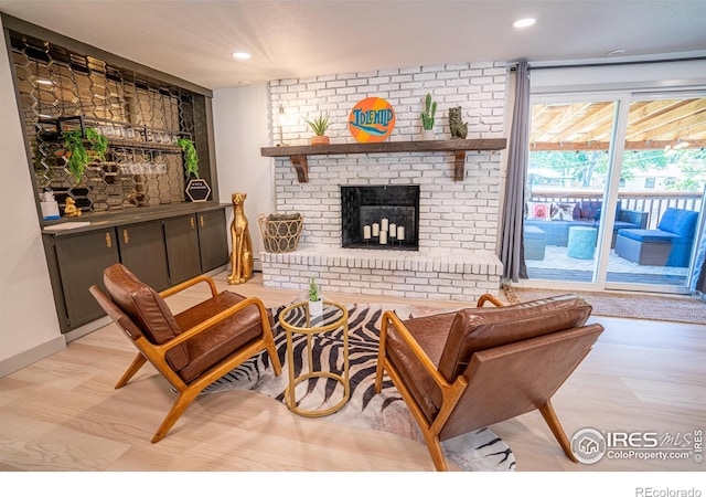 living area with baseboards, a fireplace, light wood-style flooring, and recessed lighting