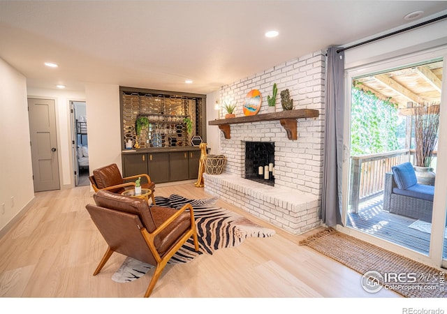 living room with a brick fireplace, light wood-style flooring, and recessed lighting