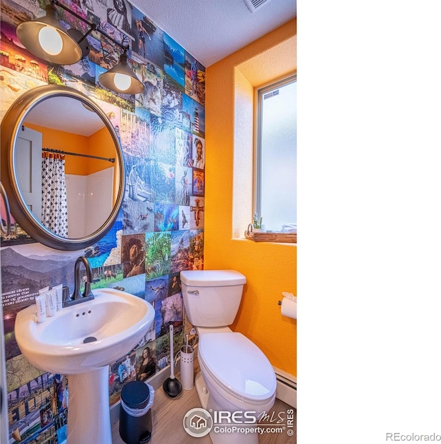 bathroom featuring a baseboard radiator, visible vents, a shower with shower curtain, toilet, and a sink