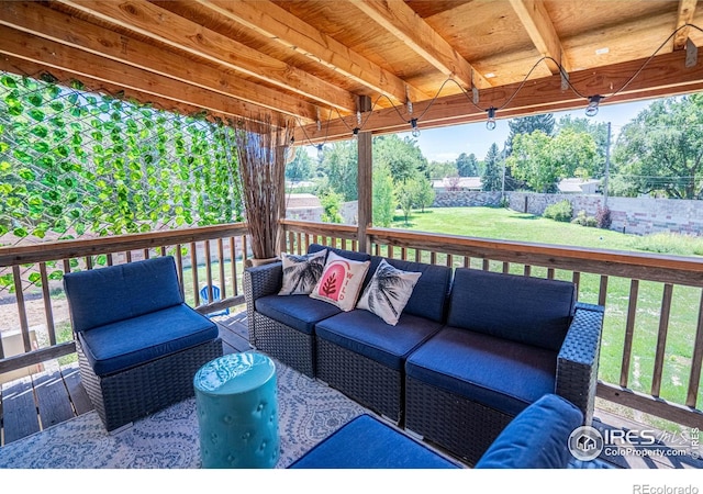 wooden terrace featuring fence, an outdoor living space, and a lawn