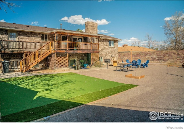 rear view of house featuring a chimney, stairway, a wooden deck, a patio area, and brick siding