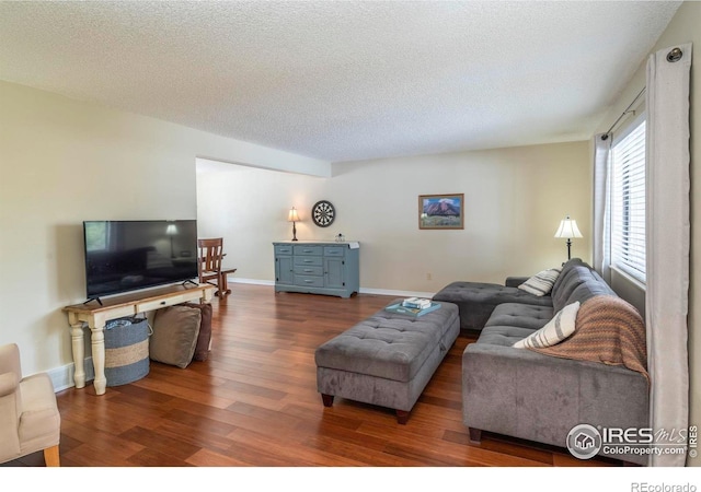 living room with a textured ceiling, baseboards, and wood finished floors