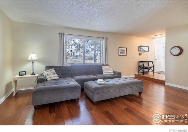 living area featuring a textured ceiling, dark wood-type flooring, and baseboards