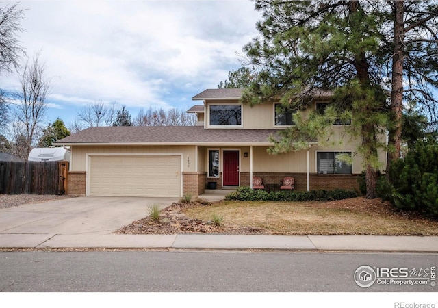 traditional-style home with a garage, concrete driveway, brick siding, and fence