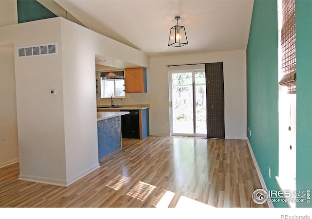 kitchen featuring visible vents, light countertops, light wood-style floors, pendant lighting, and a sink