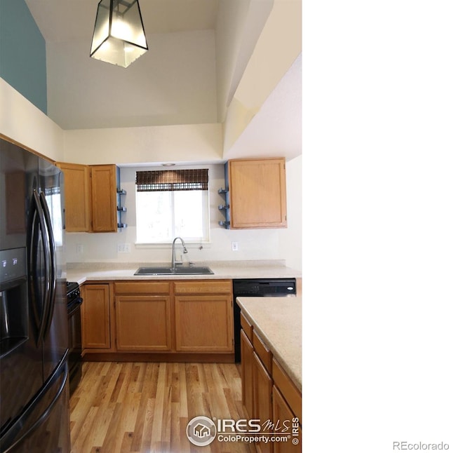 kitchen featuring light wood-style flooring, light countertops, black appliances, open shelves, and a sink