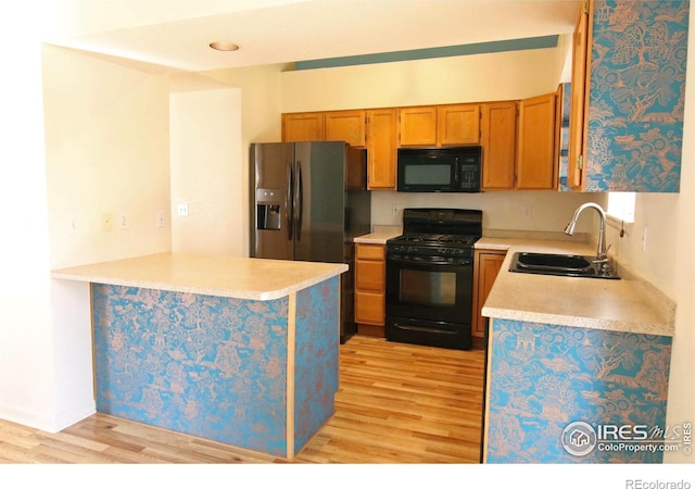 kitchen featuring black appliances, a sink, light countertops, and brown cabinets