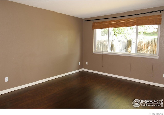 unfurnished room featuring dark wood-type flooring and baseboards