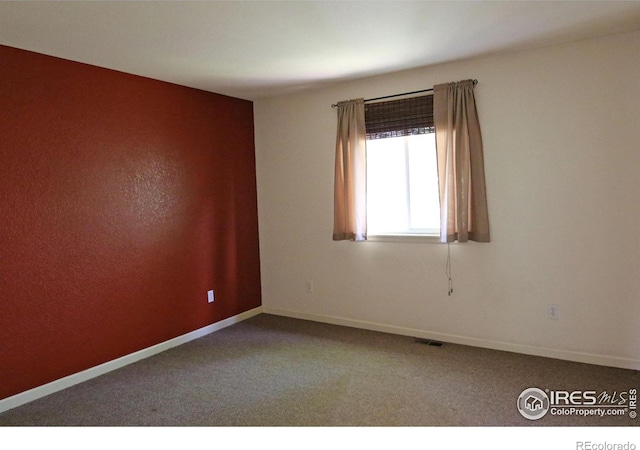 empty room featuring carpet flooring, visible vents, and baseboards