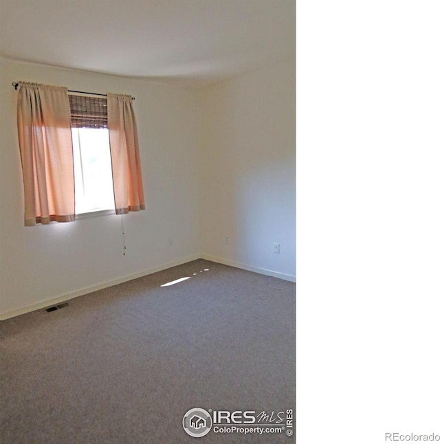 spare room featuring carpet, visible vents, and baseboards