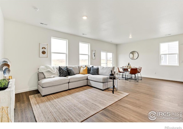 living room featuring recessed lighting, visible vents, baseboards, and wood finished floors