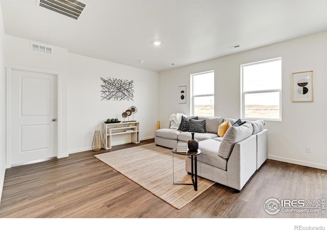 living area with wood finished floors, visible vents, and baseboards